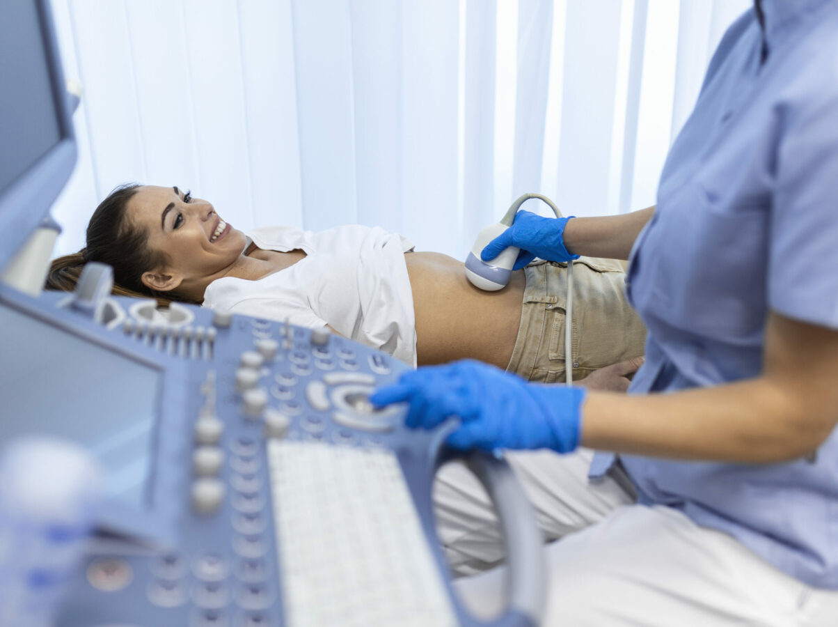 Ultrasound diagnostic of stomach on abdominal to woman in clinic, closeup view. Doctor runs ultrasound sensor over patient's girl tummy and looks at image on screen. Diagnosis of internal organs.